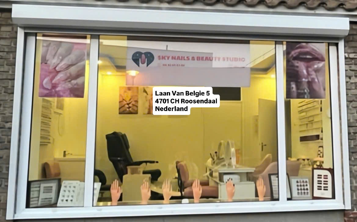 Het verlichte raam van de salon in de avond, met de banner Sky Nails & Beauty Studio